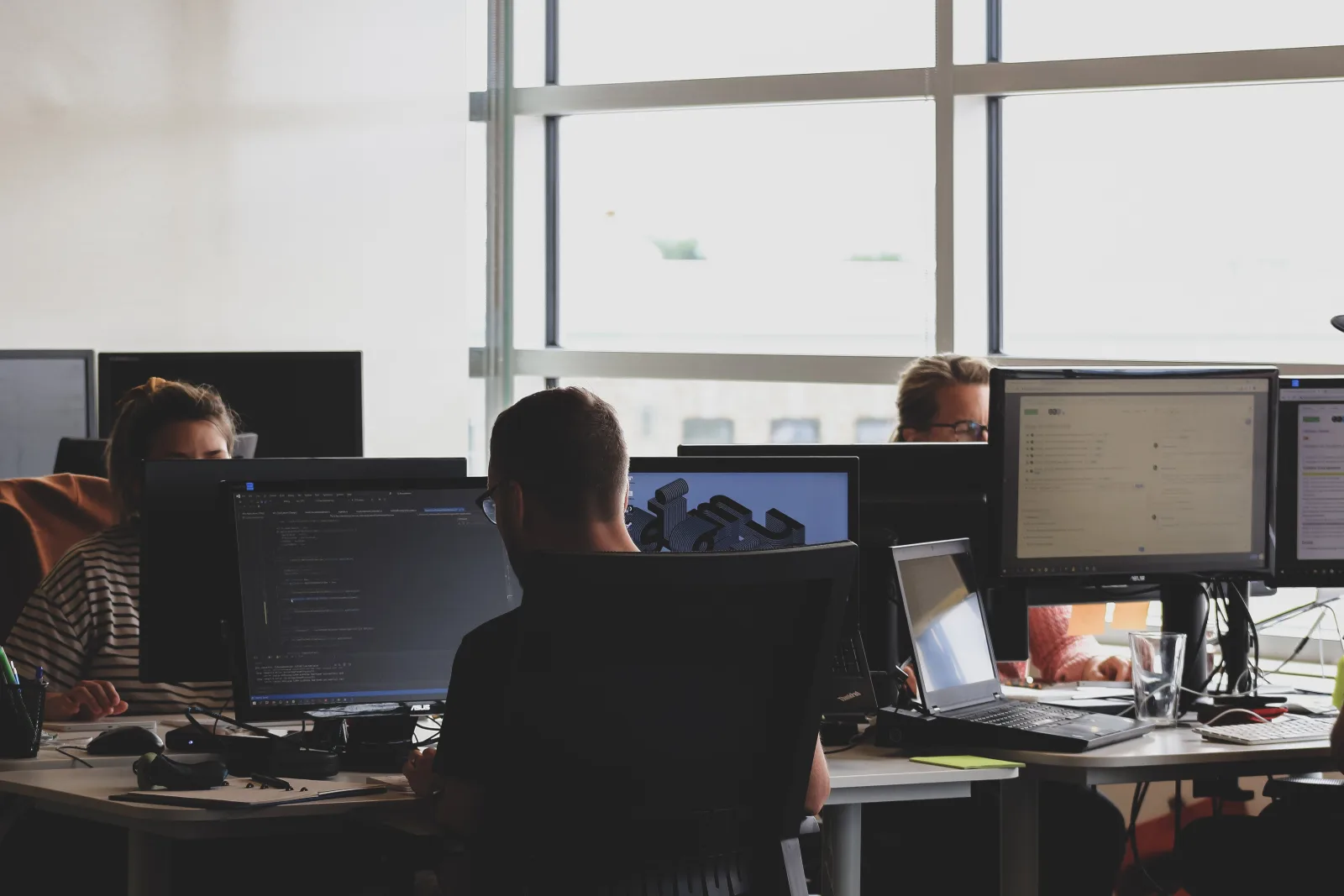 Modern open-plan office with people working at multiple monitors